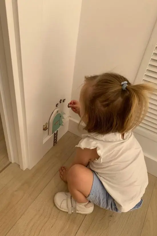 Niña pequeña pegando pegatinas en la pared del rincón infantil de la clínica